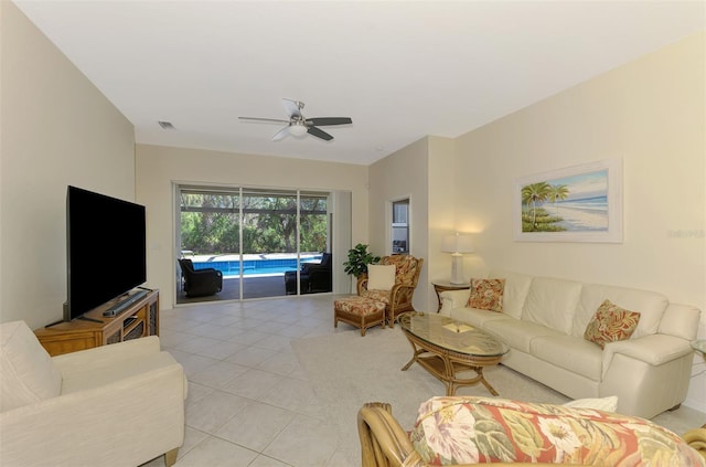 living room featuring light tile patterned floors, ceiling fan, visible vents, and a sunroom