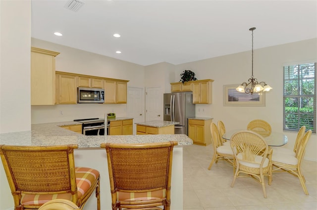 kitchen with a peninsula, light brown cabinets, appliances with stainless steel finishes, and a chandelier