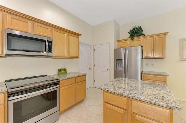 kitchen with appliances with stainless steel finishes, light brown cabinetry, light stone counters, and light tile patterned floors