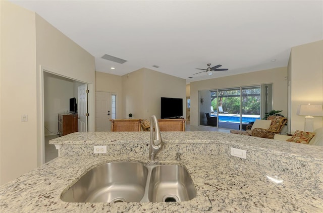 kitchen with ceiling fan, visible vents, light stone counters, and a sink