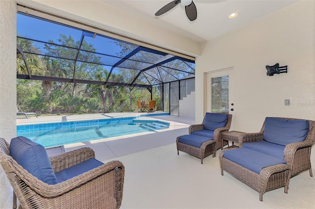 outdoor pool featuring glass enclosure, a patio area, and a ceiling fan