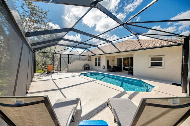 outdoor pool with a lanai, a patio area, and grilling area