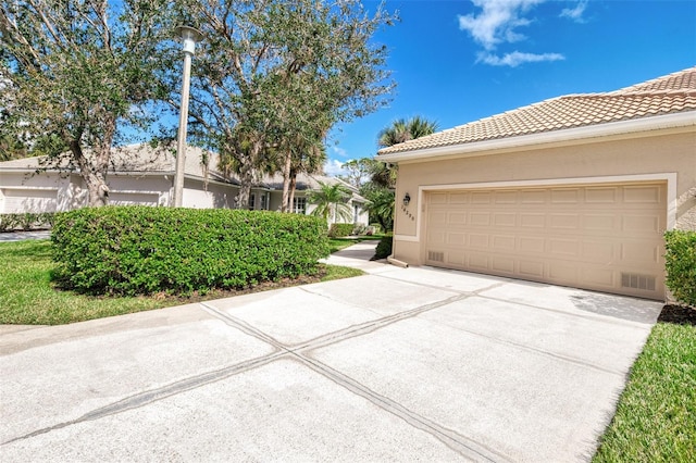 single story home featuring concrete driveway, a tiled roof, and stucco siding