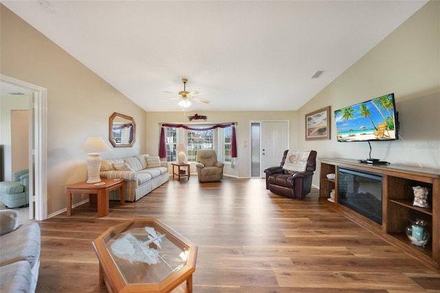 living area with vaulted ceiling, a glass covered fireplace, wood finished floors, and visible vents