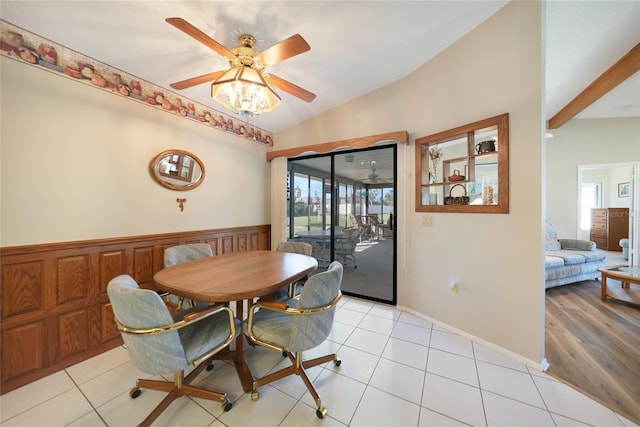 dining area with ceiling fan, wainscoting, vaulted ceiling with beams, and light tile patterned flooring