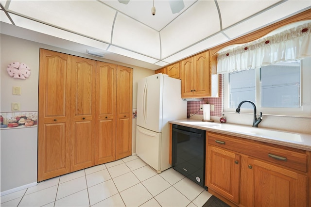 kitchen featuring light countertops, decorative backsplash, freestanding refrigerator, a sink, and dishwasher