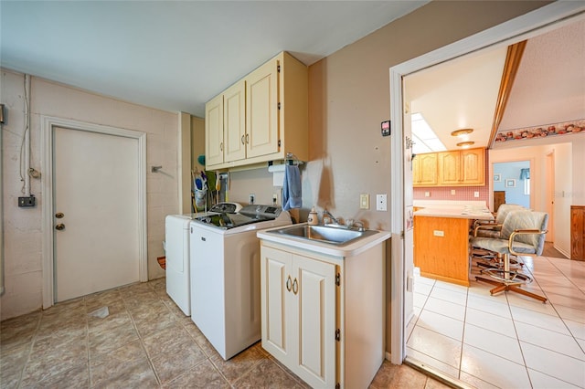 laundry room featuring cabinet space, washing machine and dryer, light tile patterned floors, and a sink