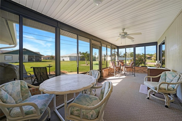 sunroom featuring ceiling fan and a residential view