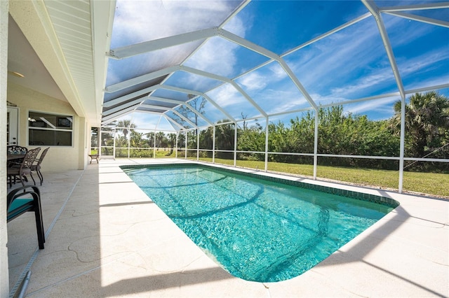 outdoor pool featuring glass enclosure, a lawn, and a patio