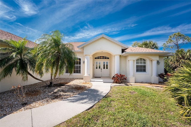 mediterranean / spanish house featuring roof with shingles, a front yard, french doors, and stucco siding