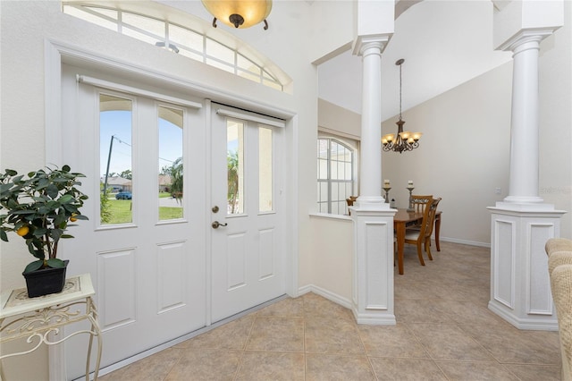 entrance foyer featuring light tile patterned floors, lofted ceiling, decorative columns, and a notable chandelier