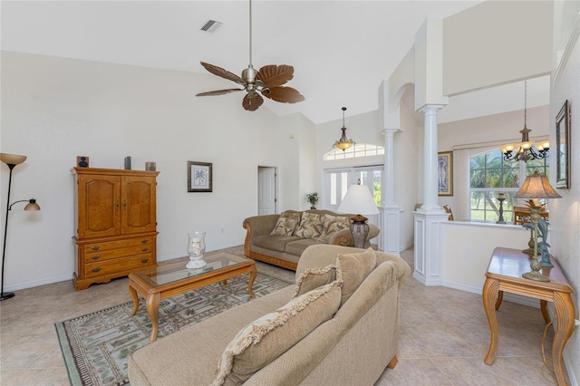 living room featuring light tile patterned floors, high vaulted ceiling, ceiling fan with notable chandelier, visible vents, and decorative columns