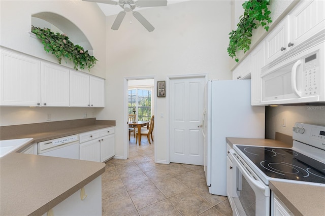 kitchen with white appliances, light tile patterned floors, white cabinets, a ceiling fan, and a high ceiling