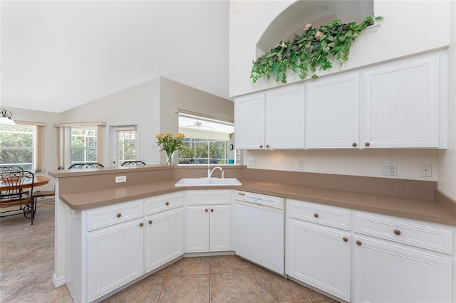 kitchen with white cabinets, a peninsula, a sink, white dishwasher, and a wealth of natural light