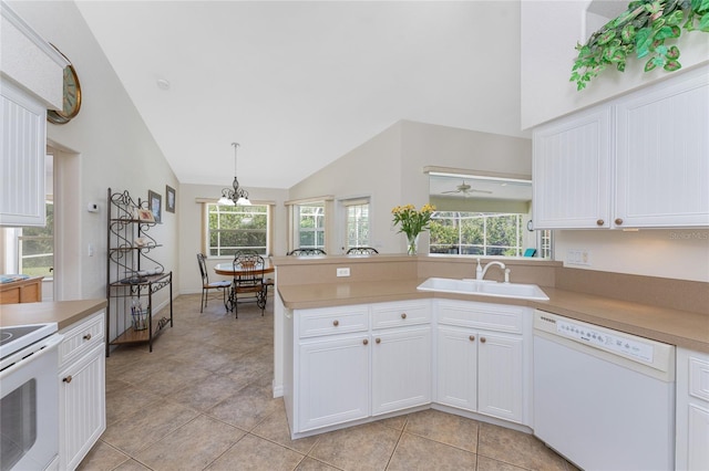 kitchen featuring decorative light fixtures, light countertops, white cabinets, a sink, and white appliances