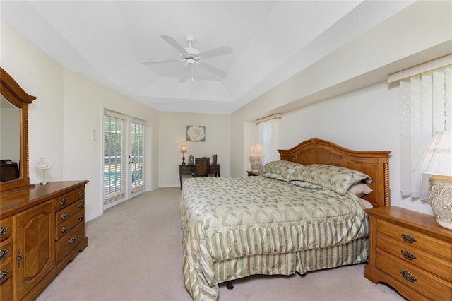 bedroom with access to exterior, a tray ceiling, light carpet, and ceiling fan