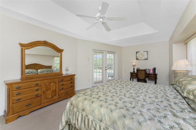 bedroom with light colored carpet, ceiling fan, access to exterior, a tray ceiling, and french doors