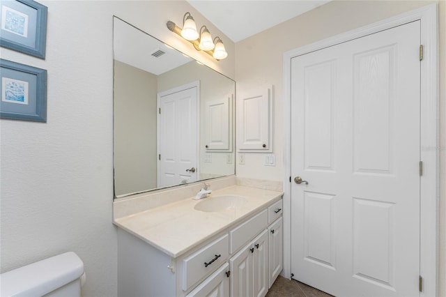 half bathroom with toilet, vanity, and visible vents