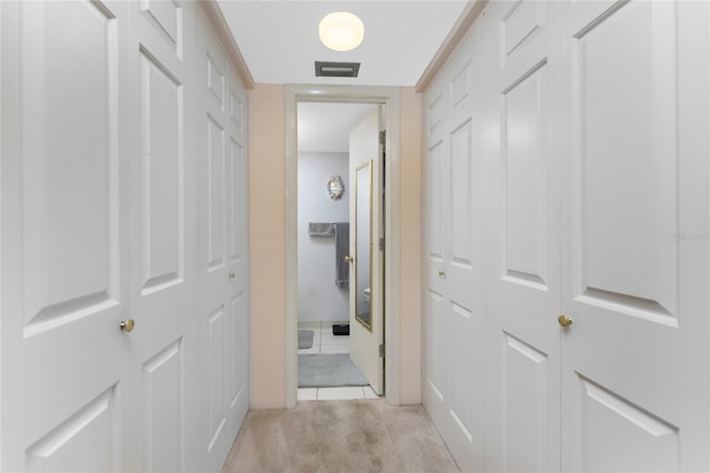 hallway with visible vents and light colored carpet