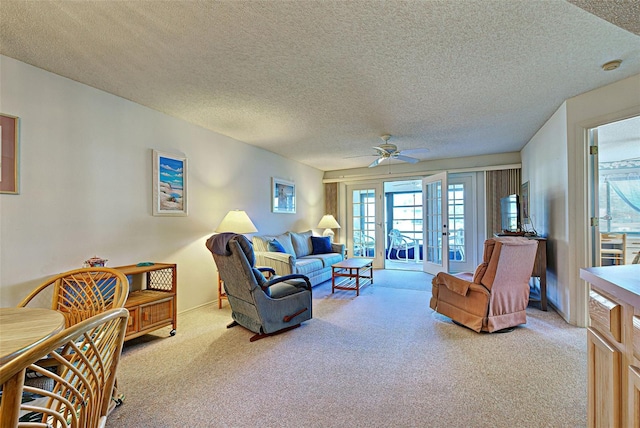 living area featuring light colored carpet, ceiling fan, and a textured ceiling