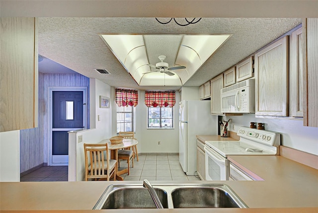 kitchen with light tile patterned floors, white appliances, a sink, visible vents, and light countertops