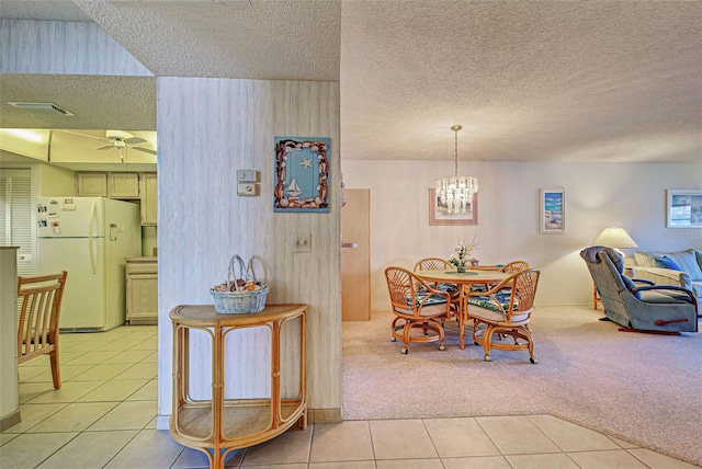 dining area with light carpet, light tile patterned floors, and a textured ceiling