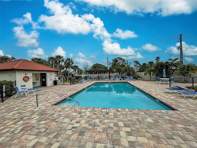 community pool with a patio area and fence