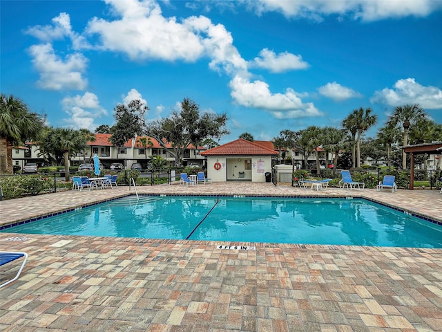 community pool with a patio and fence