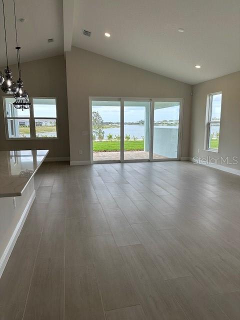 interior space featuring an inviting chandelier, visible vents, baseboards, and vaulted ceiling