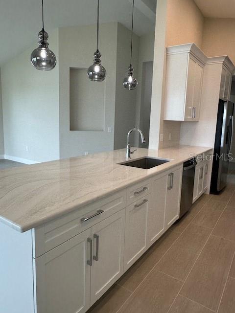 kitchen featuring white cabinets, light stone counters, stainless steel appliances, and a sink