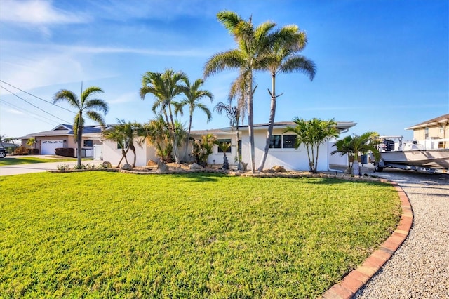 single story home with a garage, concrete driveway, a front yard, and stucco siding