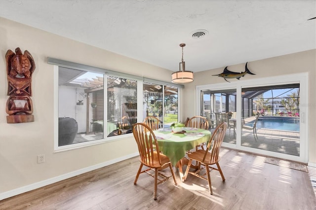 dining room featuring visible vents, wood finished floors, a sunroom, and baseboards