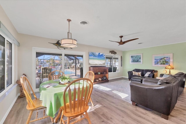 dining space featuring a sunroom, baseboards, and light wood finished floors