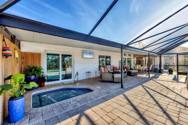 exterior space featuring an in ground hot tub, glass enclosure, a patio, and an outdoor hangout area