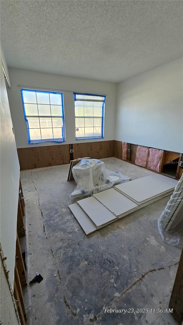 unfurnished bedroom featuring a wainscoted wall, a textured ceiling, and wooden walls