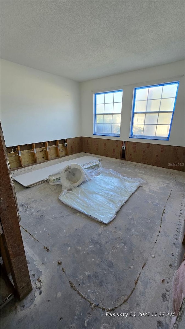 spare room with a textured ceiling and wooden walls