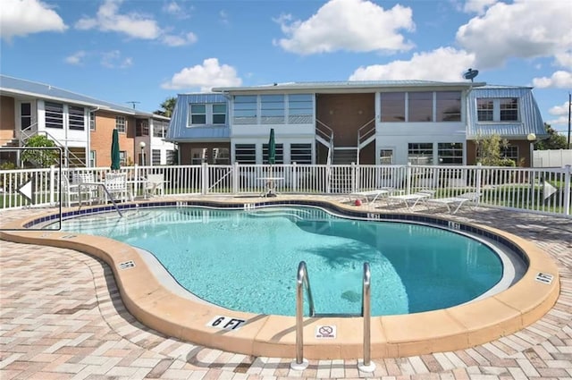 pool with a patio area and fence