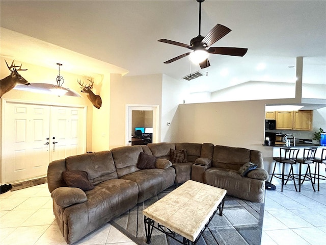 living area featuring light tile patterned floors, visible vents, a ceiling fan, and lofted ceiling