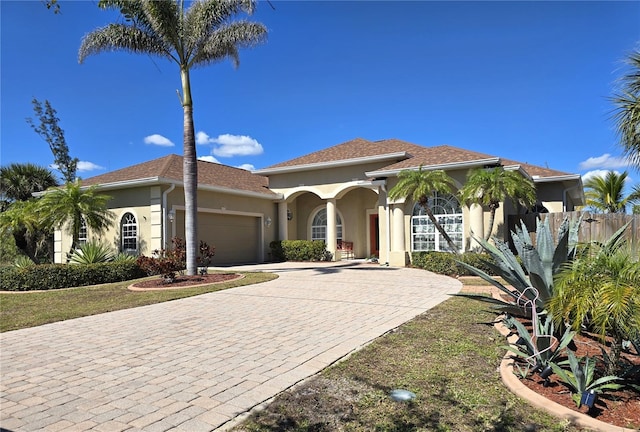 mediterranean / spanish house featuring a garage, decorative driveway, and stucco siding