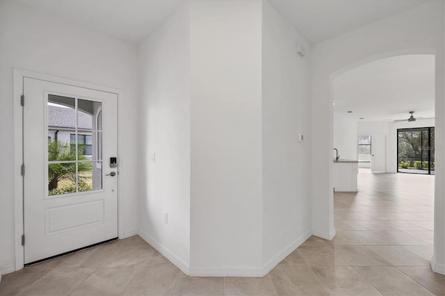 entrance foyer featuring arched walkways, light tile patterned floors, and baseboards