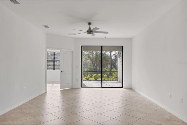 spare room featuring a ceiling fan, visible vents, baseboards, and light tile patterned floors