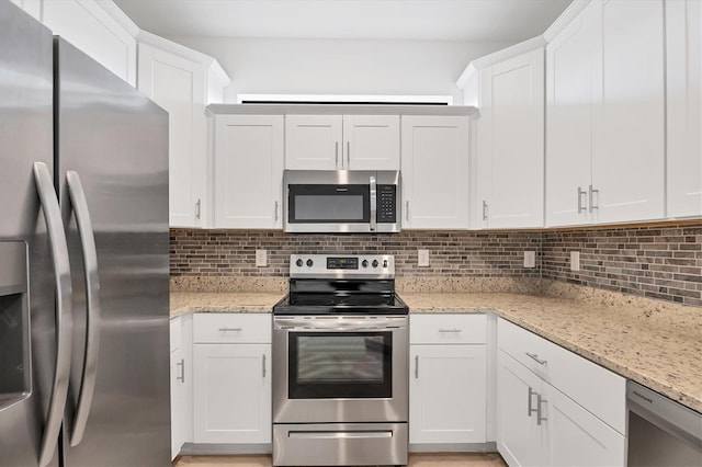 kitchen featuring stainless steel appliances, light stone counters, backsplash, and white cabinets