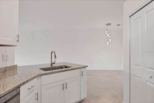 kitchen with light stone countertops, dishwasher, white cabinets, and a sink