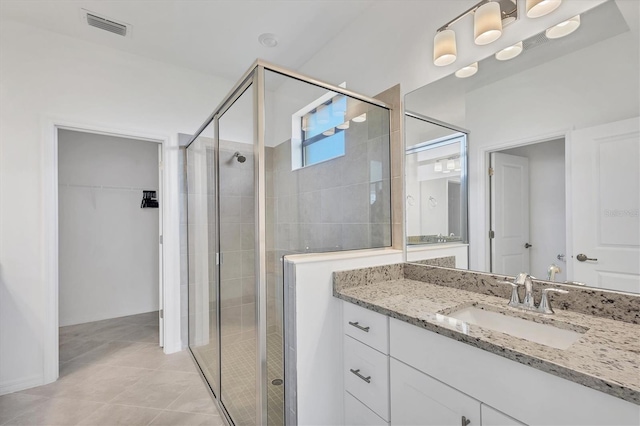 bathroom featuring visible vents, a spacious closet, a stall shower, vanity, and tile patterned flooring