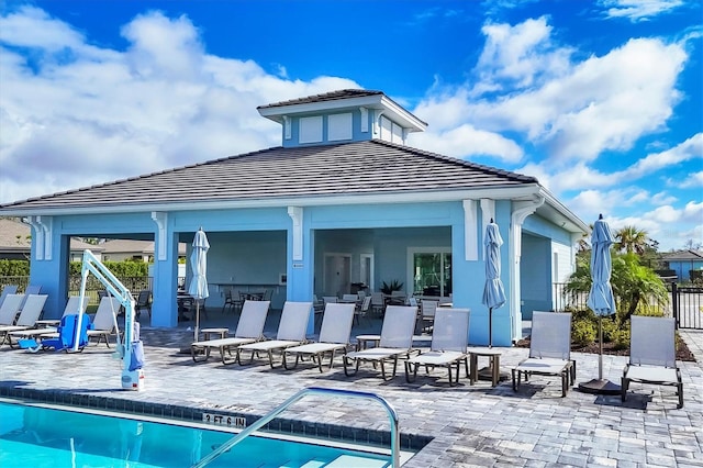 back of property featuring a tile roof, a patio area, fence, and a community pool