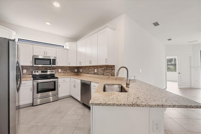 kitchen featuring stainless steel appliances, visible vents, backsplash, a sink, and a peninsula