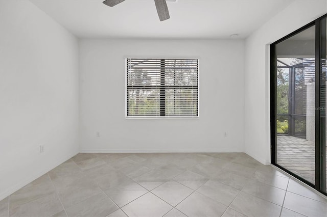 empty room with ceiling fan, light tile patterned floors, and baseboards