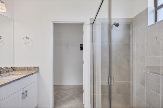 bathroom with tile patterned flooring, a shower stall, vanity, and a spacious closet