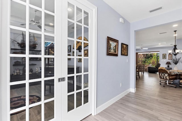 interior space with baseboards, an inviting chandelier, visible vents, and light wood-style floors