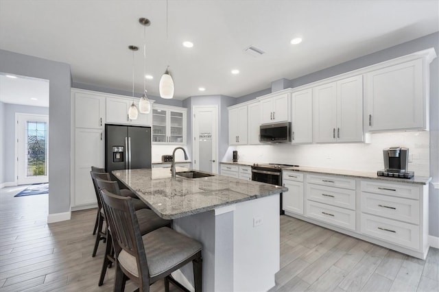 kitchen featuring backsplash, a center island with sink, stainless steel appliances, and a sink